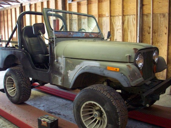 1978 Jeep CJ5 on a lift, showing front quarter view with roll bar and aftermarket wheels