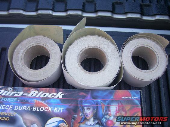 Three rolls of sandpaper and a Dura-Block kit box with clown graphics
