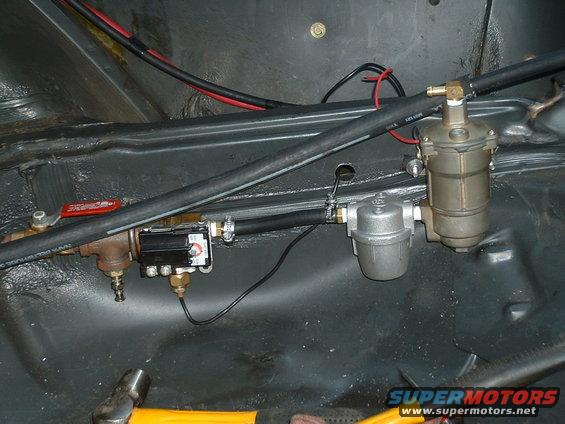 Close-up of a fuel filter and pump assembly with hoses and wiring