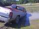 1995 Dodge 1500 - A red and silver pickup truck is stuck in the mud near a body of water with some branches sticking out.