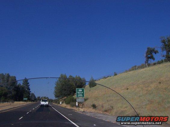 White pickup truck driving on highway, Sonora Pass sign visible