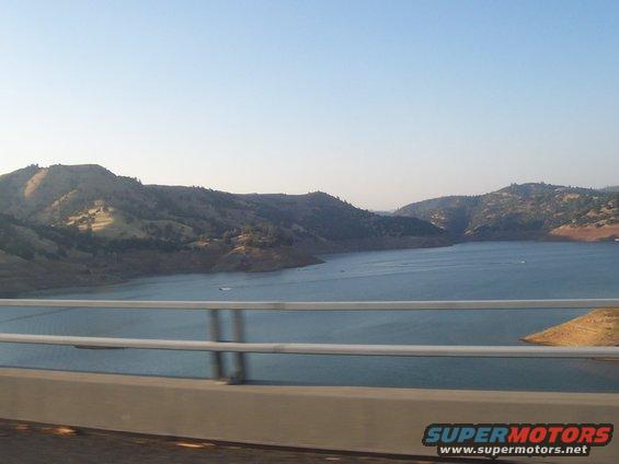 Water reservoir with hills and a bridge railing in the foreground