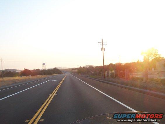Highway stretching into the distance at sunset with a water tower on the left