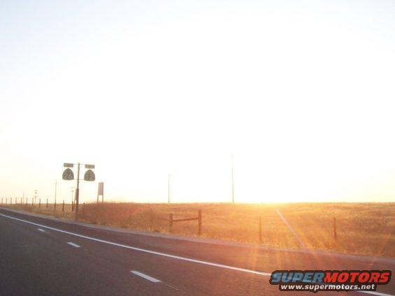 Roadside signs with numbers 26 and 12 under a bright sunset