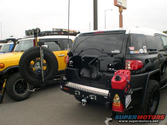Black 2007 Toyota FJ Cruiser rear view with a yellow FJ Cruiser to the left