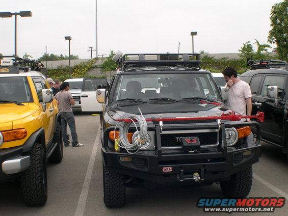 Black 2007 Toyota FJ Cruiser parked next to a yellow one, both with roof racks