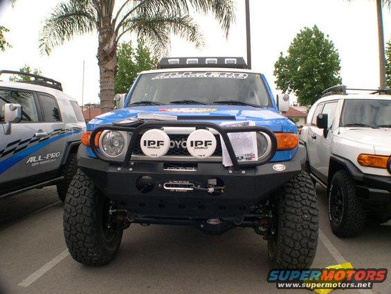 Blue 2007 Toyota FJ Cruiser with aftermarket bumper and IPF lights, parked next to a white FJ Cruiser