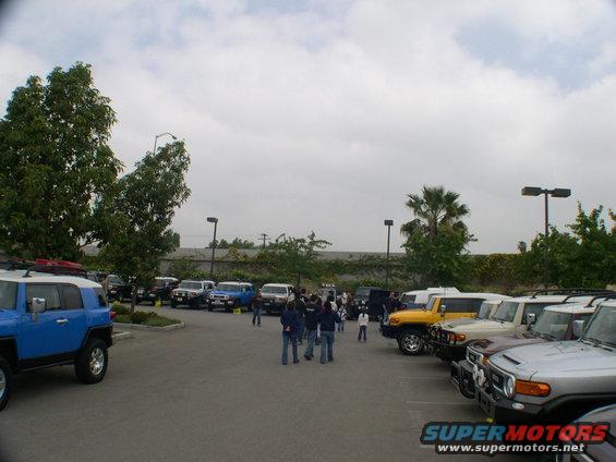 Several Toyota FJ Cruisers parked in a lot, some people milling around
