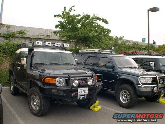 2007 Toyota FJ Cruiser with snorkel and roof lights parked next to a dark green Toyota 4Runner