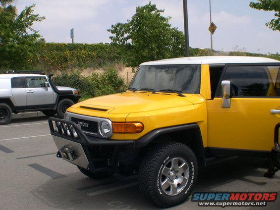 Yellow 2007 Toyota FJ Cruiser parked next to a silver FJ Cruiser