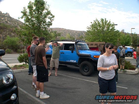 Blue Toyota FJ Cruiser with snorkel and roof rack, parked in a lot with people around