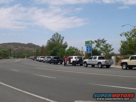 Line of Toyota FJ Cruisers and Tacomas parked on roadside with 'Park & Ride' sign