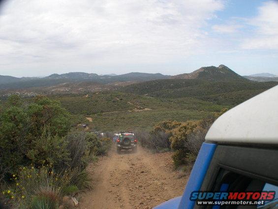 Blue 2007 Toyota FJ Cruiser driving on a dirt road, rear view