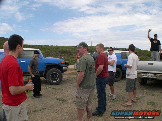 2007 Toyota FJ Cruiser parked on dirt with people around it, silver pickup truck also visible