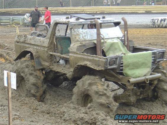 Mud bogging truck stuck in thick mud, with large tires and exposed engine components