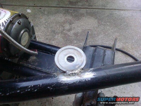 Welded bracket on black metal tube with silver washer and part of electric motor.