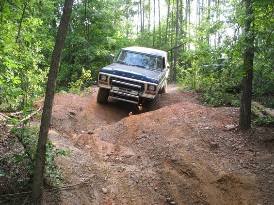 1978 Ford Bronco navigating a steep dirt path in a wooded area
