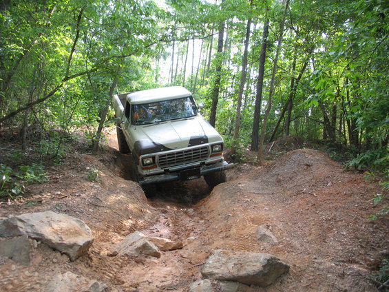 Tan and brown Ford F-Series truck navigating a dirt trail with large rocks