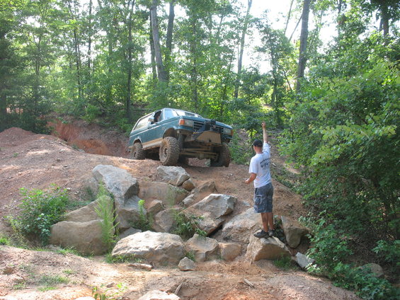 Teal SUV with lifted suspension and off-road tires navigating a rocky incline