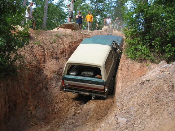1978 Ford Bronco descending a steep dirt gully with people watching from above