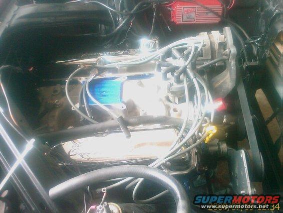 Engine bay with chrome valve covers, blue intake manifold, and red MSD ignition box. Wires and hoses are visible