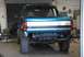 1996 Ford Bronco - The rear of a teal Ford Bronco is shown in a garage, with its bumper removed and large off-road tires installed.