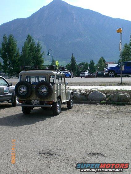 Tan 1970s Toyota Land Cruiser FJ40, rear view, with dual spare tires and roof rack