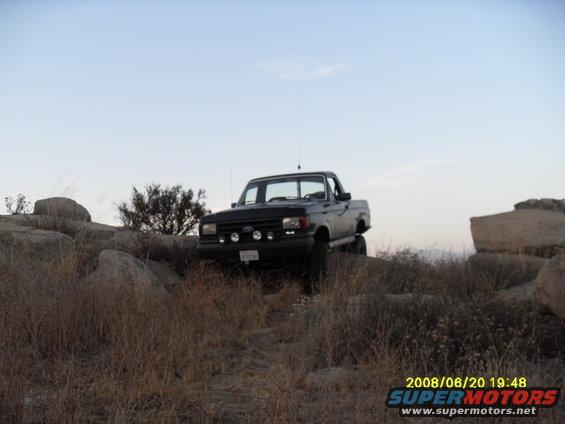 Black 1990 Ford Bronco off-roading on rocky terrain