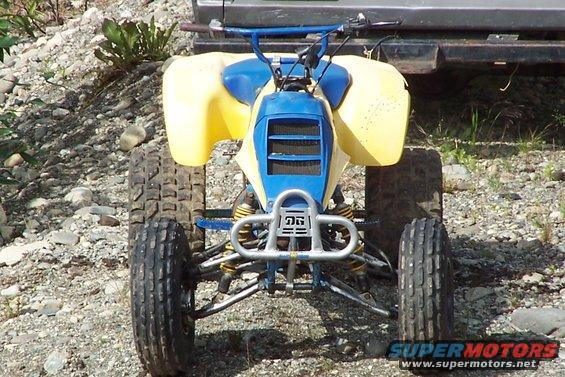 Front view of a yellow and blue ATV with knobby tires and a silver bumper