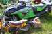 1989 Ford Bronco II - An Arctic Cat Sabercat 600 snowmobile is parked in a grassy area with other vehicles and parts.