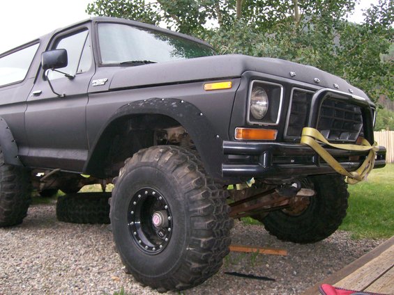 Black Ford Bronco with large tires, lifted suspension, and a custom bumper. The front grille and headlights are visible