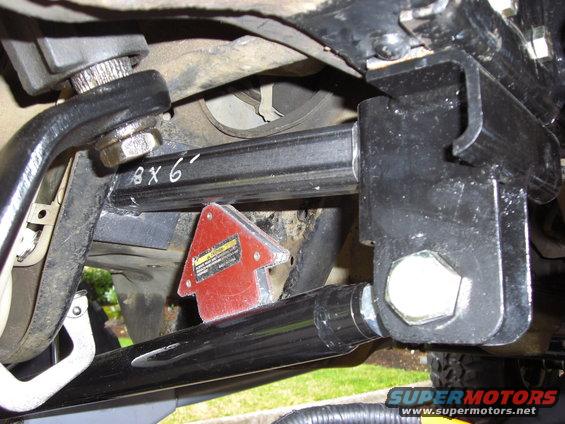 Black metal suspension arm with "8 x 6" written in white, attached to a bracket with a red magnetic arrow