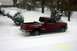 1991 Ford Crown Victoria LTD - A red pickup truck navigates through a snowy landscape, kicking up snow as it drives.