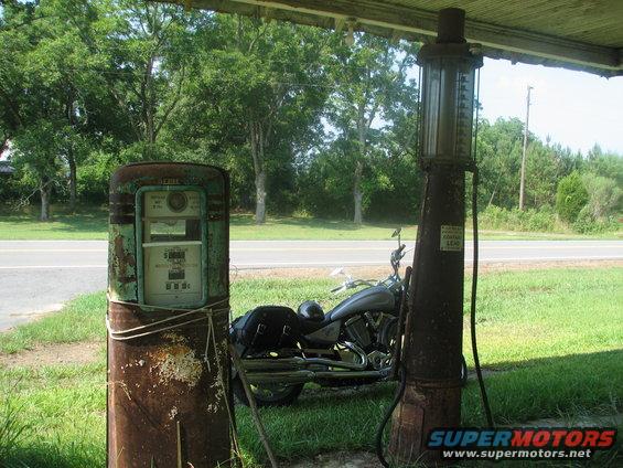 Motorcycle parked between two vintage gas pumps