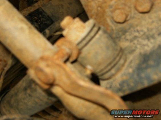 Close-up of rusted suspension parts, including a tie rod end and a shock absorber mount