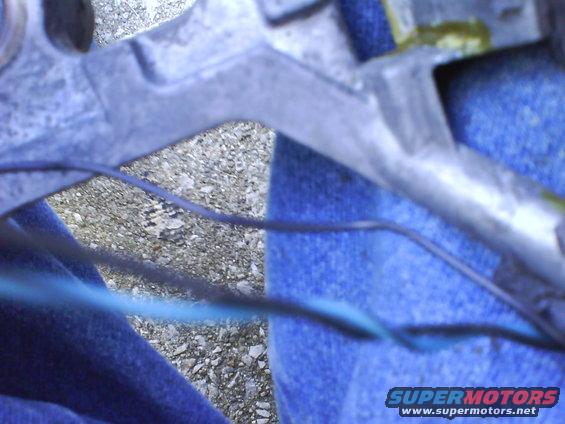 Close-up of a metal suspension component with blue wires running across it