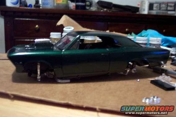 Green model car body with no wheels, on a cardboard surface
