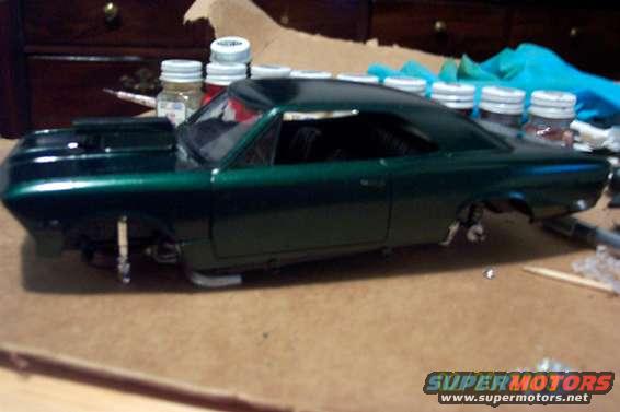 Green model car kit, partially assembled, on a table with jars and tools
