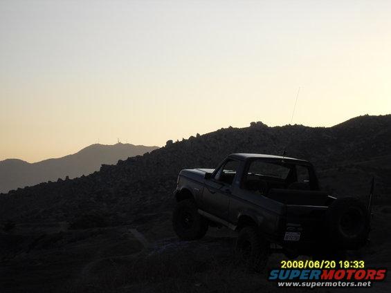 Ford Bronco parked on a rocky hill at sunset
