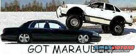 Black sedan low to ground, white sedan lifted on top of it, in a snowy area