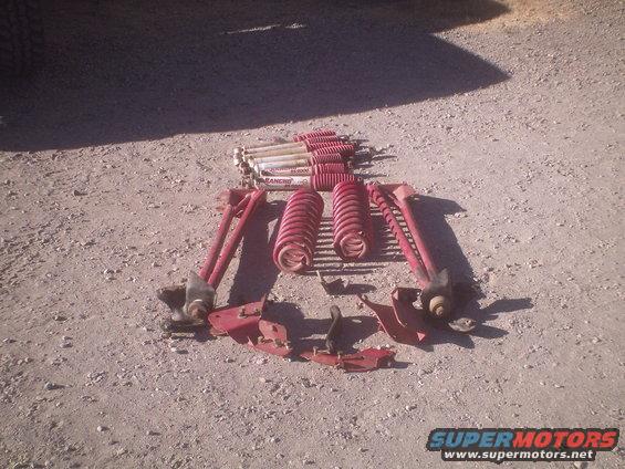 Red suspension parts including shocks and springs laid out on the ground