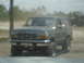 1989 Ford Bronco - Front view of a 1989 Ford Bronco, with another vehicle in the background.