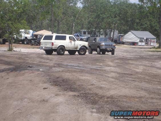 White SUV from the late 1980s parked on dirt, with another SUV nearby