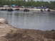 1989 Ford Bronco - Off-road trucks participate in a mud bog event with spectators watching from the shore.