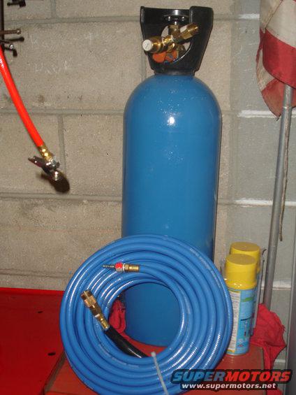 Blue air compressor tank with coiled blue hose and red air hose attached to a clip