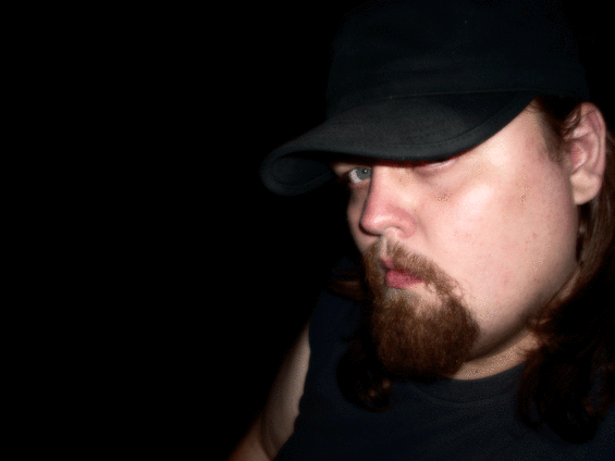 Man in black cap and goatee, dark background
