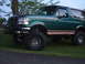 1996 Ford Bronco - A lifted 1996 Ford Bronco in green with tan trim is shown from a 3/4 front angle.