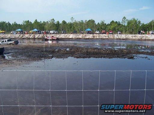 Mud bog event with trucks stuck in mud and spectators watching