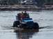 1989 Ford Bronco - A group enjoys a ride in a custom blue off-road vehicle through a muddy water area.