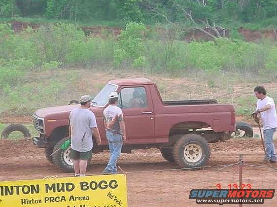 Red SUV from the early 1980s, side view, with three people standing nearby